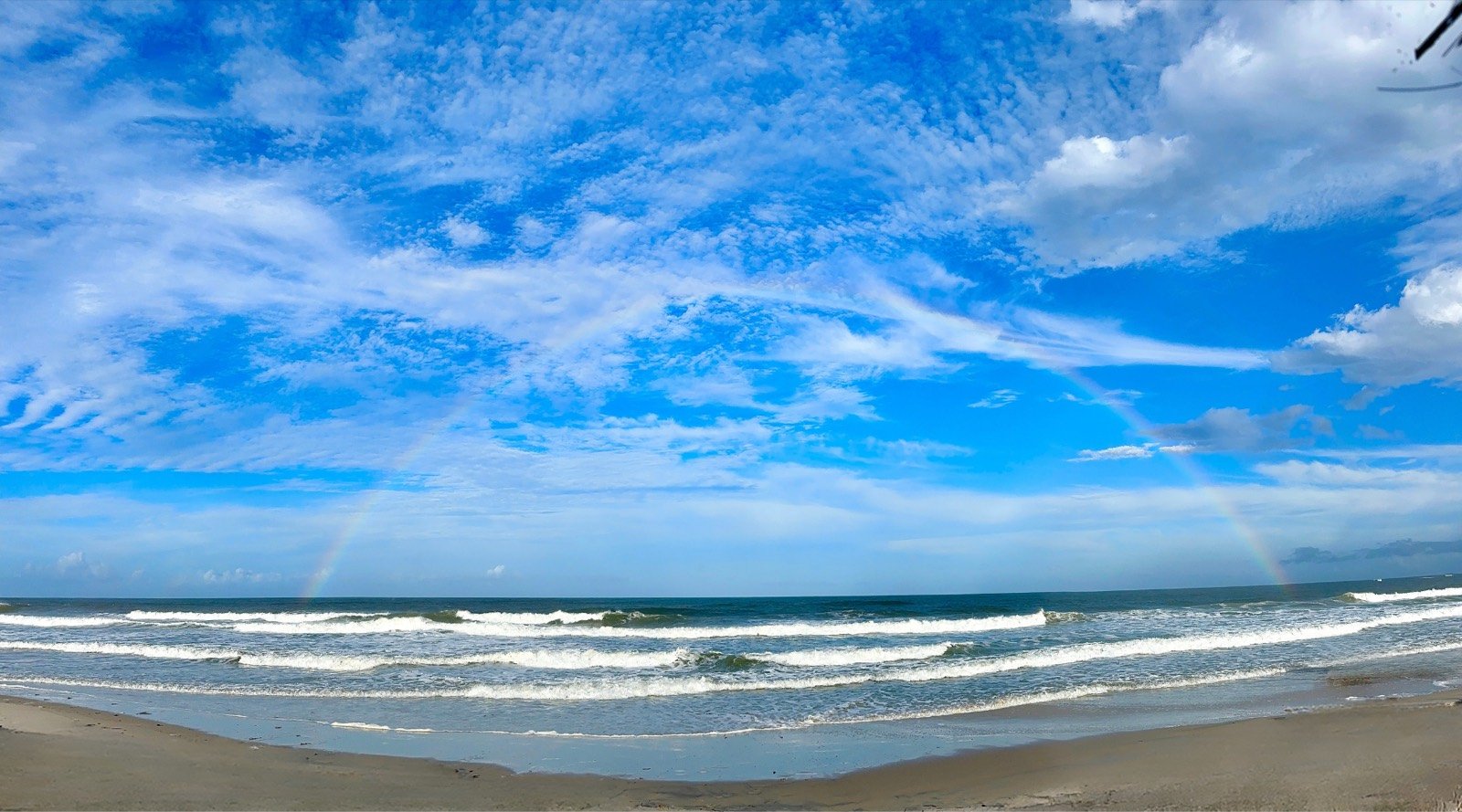 Praia de Olivença com arco-íris sobre o mar
