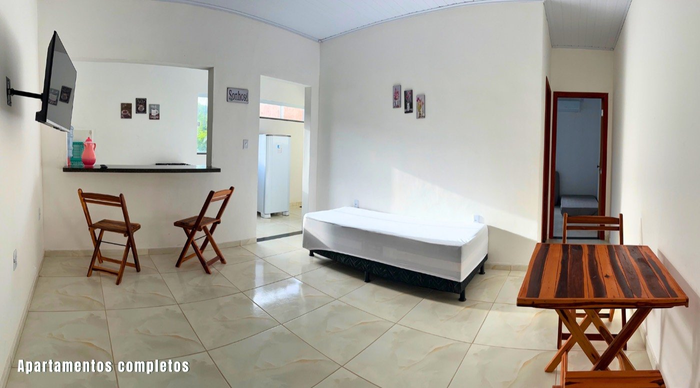 Sala de estar do apartamento com TV, mesa e bancada